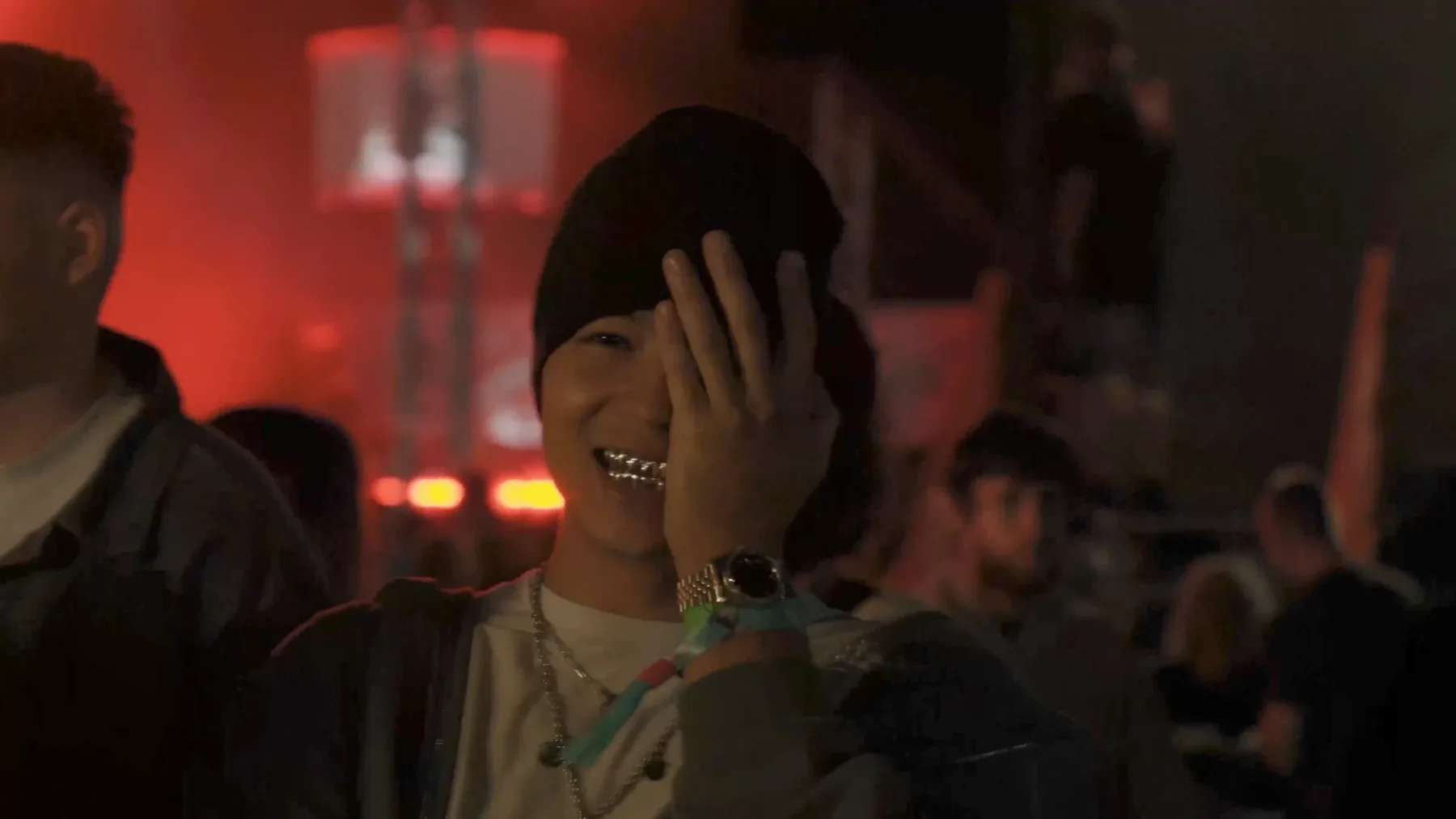 JULI3N laughing in a red-lit crowd