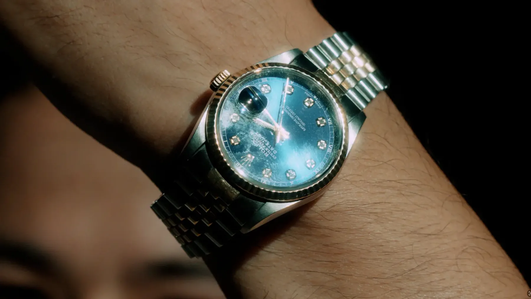 Gold and steel wristwatch catching low light on a wrist