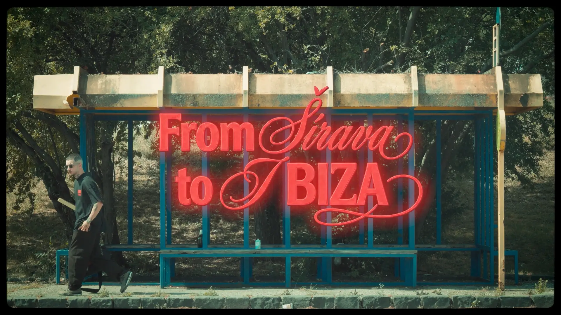 Red neon sign reading From Šírava to Ibiza on a roadside shelter