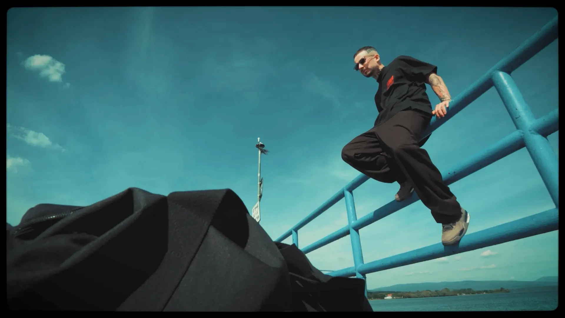 TREZOR climbing a blue pier railing under a deep blue sky